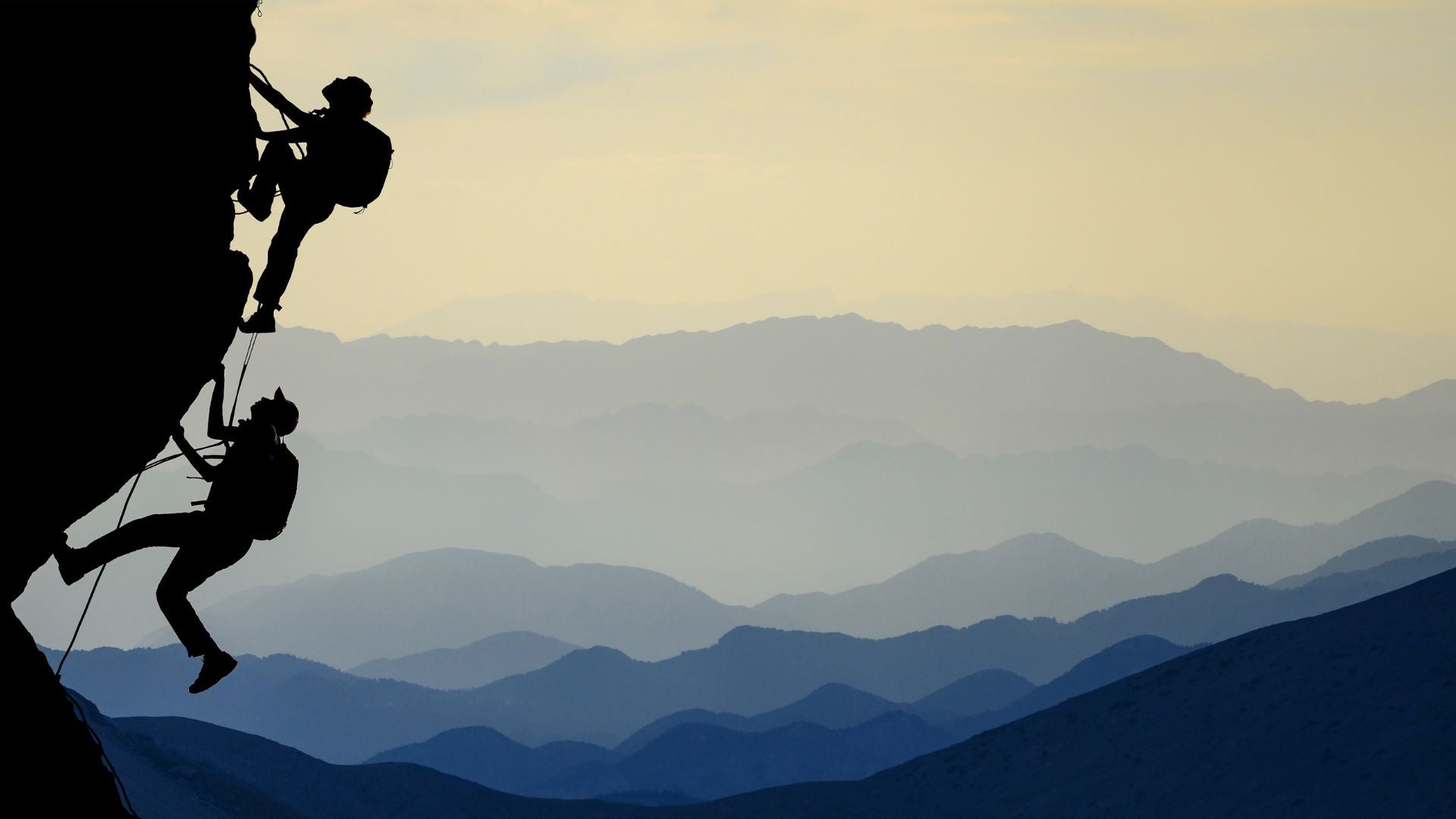 Two people climbing a cliff