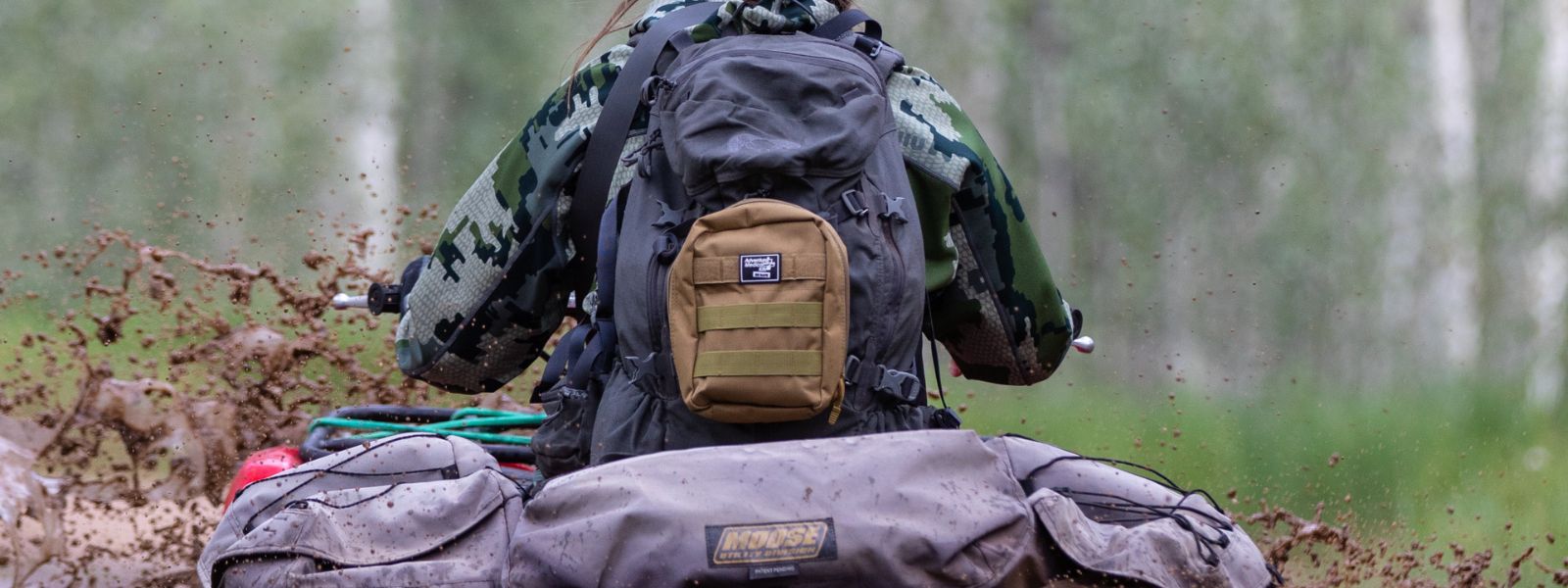 Person on ATV wearing MOLLE Kit on backpack while in mud