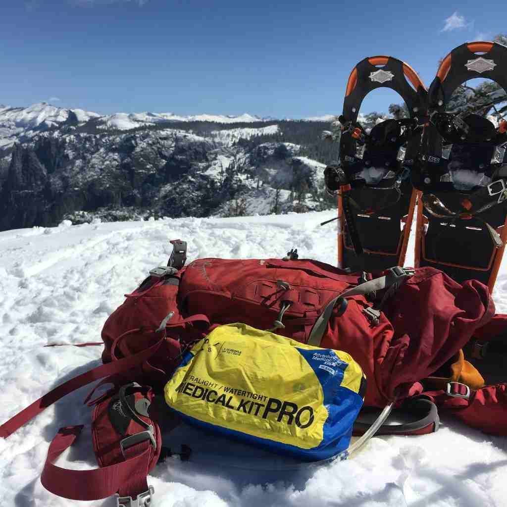 Ultralight/Watertight Medical Kit - Pro next to backpack and snowshoes in the snow