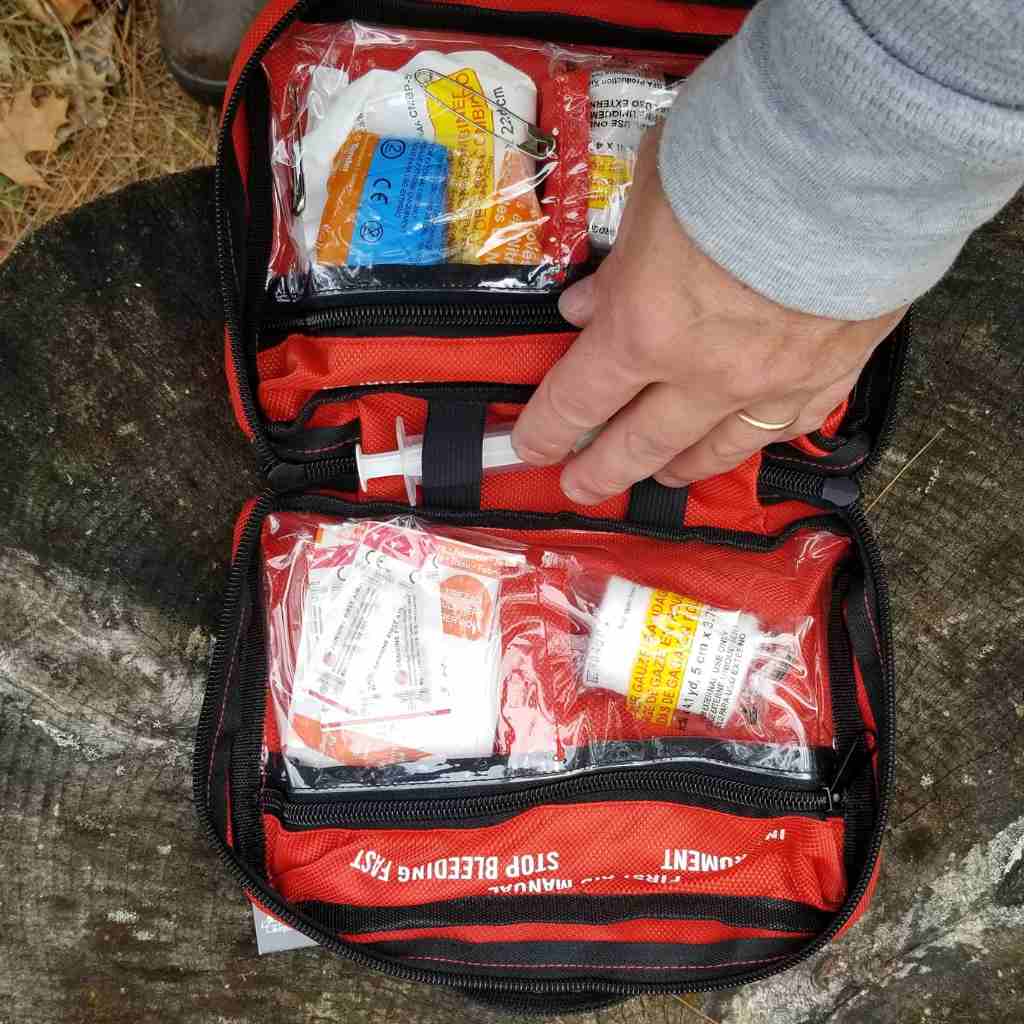 Sportsman Series Medical Kit - 200 kit opened with person touching contents on stump