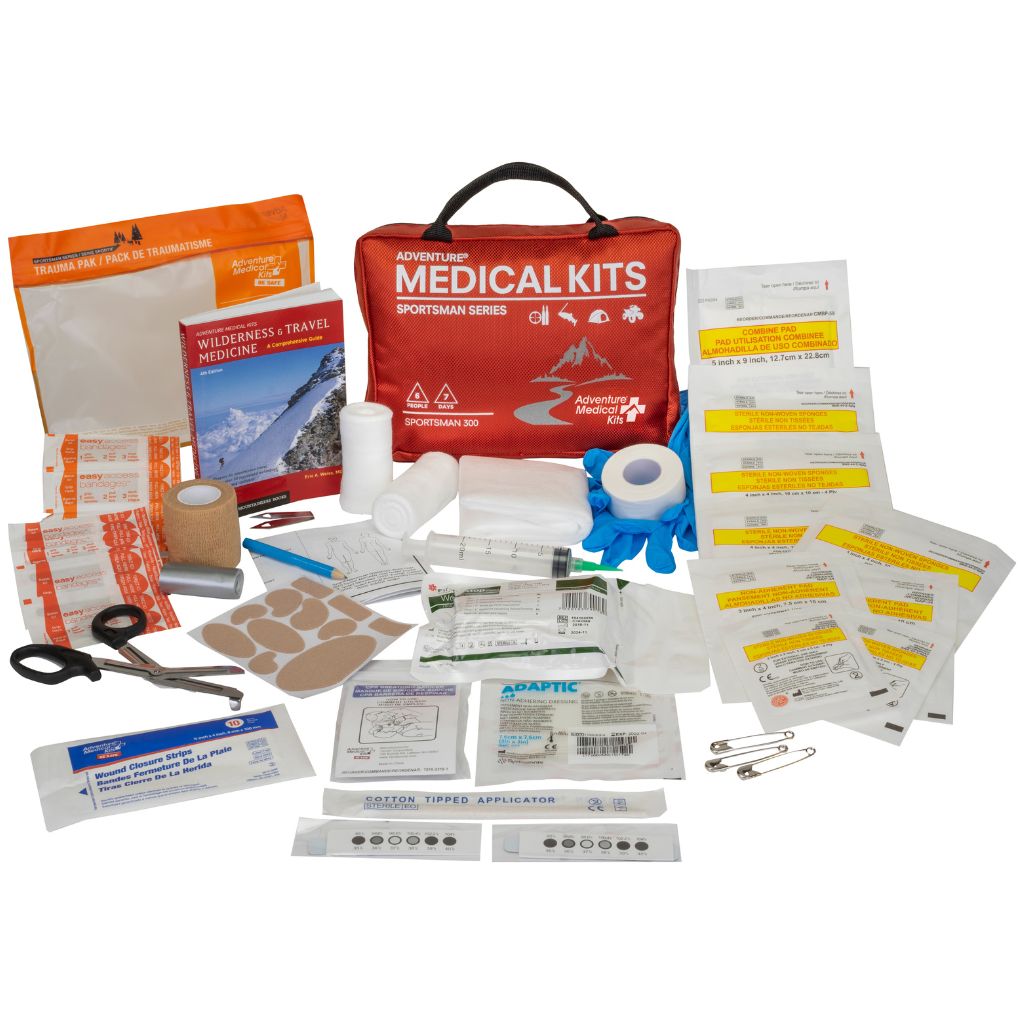 A comprehensive first aid and emergency medical kit set displayed on a clean white background, featuring a red zippered bag surrounded by various medical supplies including bandages, scissors, tweezers, and safety pins.