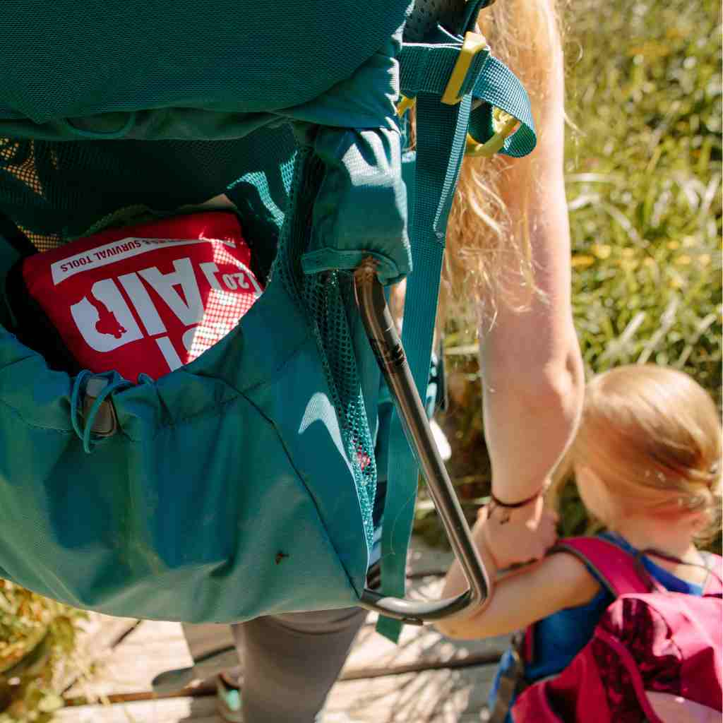 Adventure First Aid, 2.0 woman with kit in backpack holding a child's hand while hiking