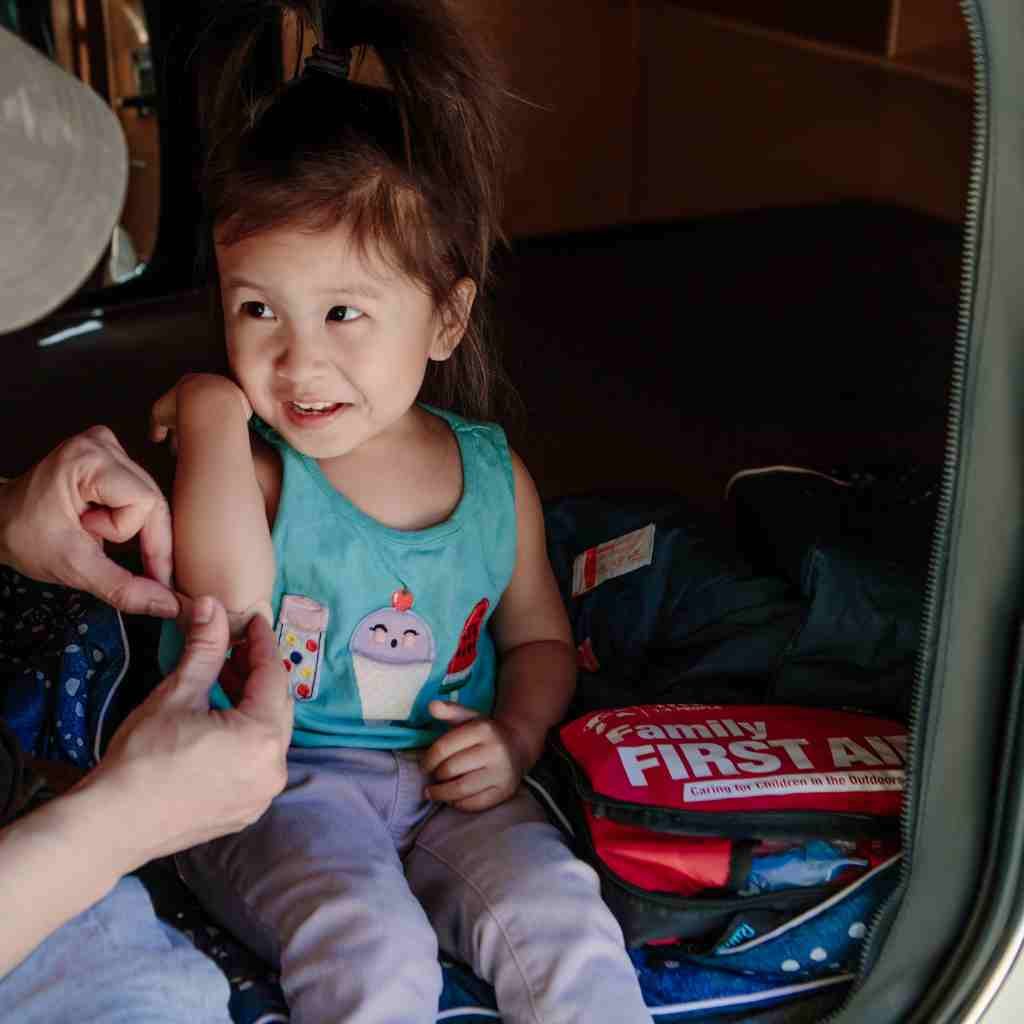 Adventure First Aid, Family First Aid Kit man attending to cut on child's arm while seated next to kit