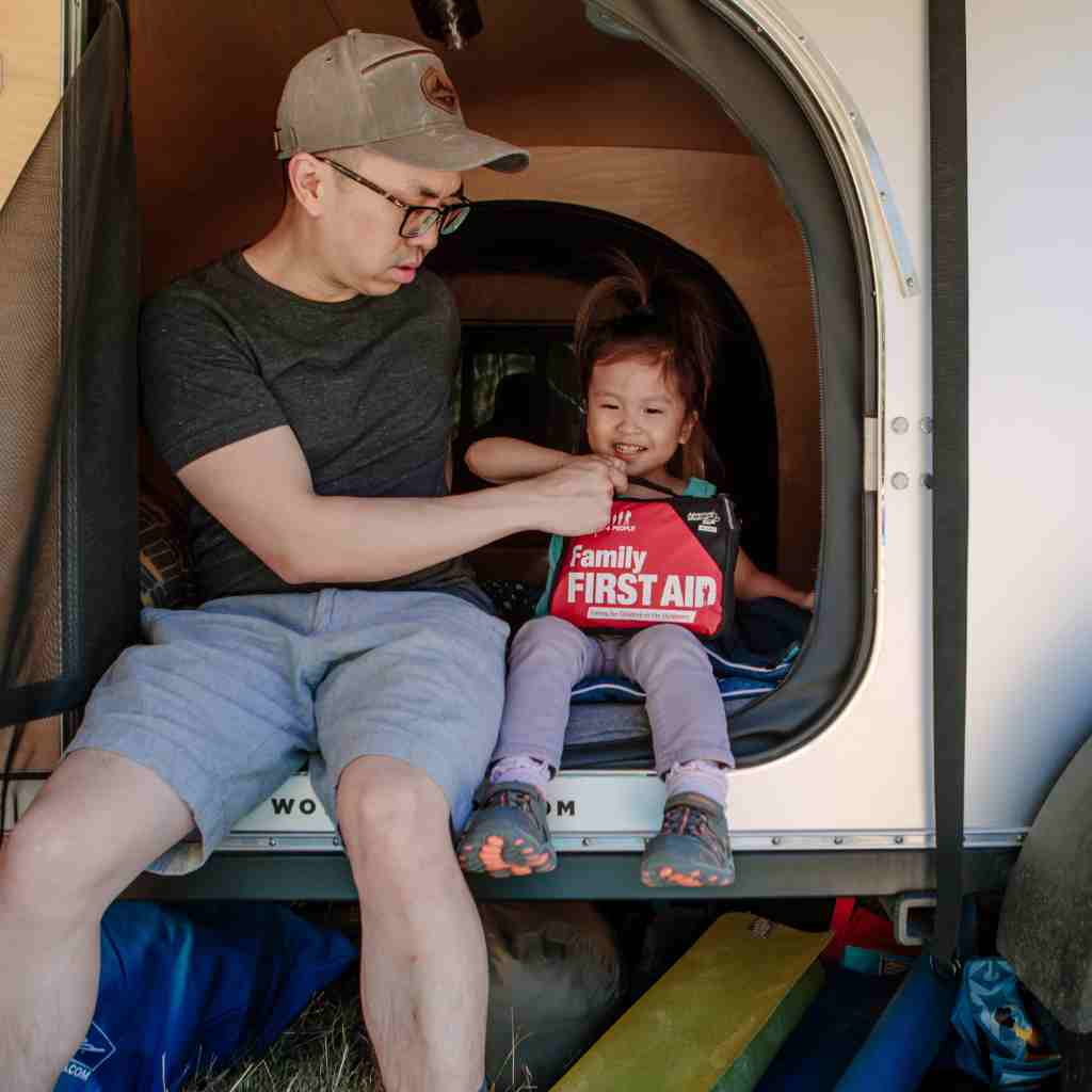 Adventure First Aid, Family First Aid Kit man and child in van entrance with kit on child's lap