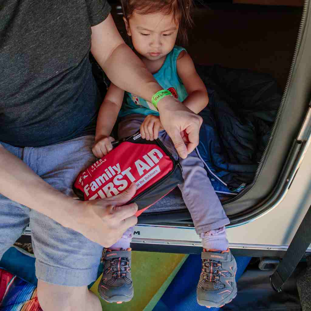 Adventure First Aid, Family First Aid Kit man opening kit over child while seated in van entrance