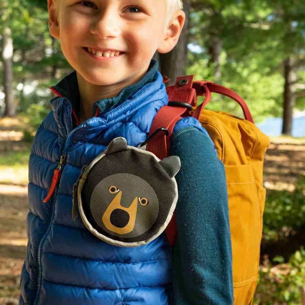 Backyard Adventure Bear First Aid Kit kit attached to front of smiling child's backpack strap