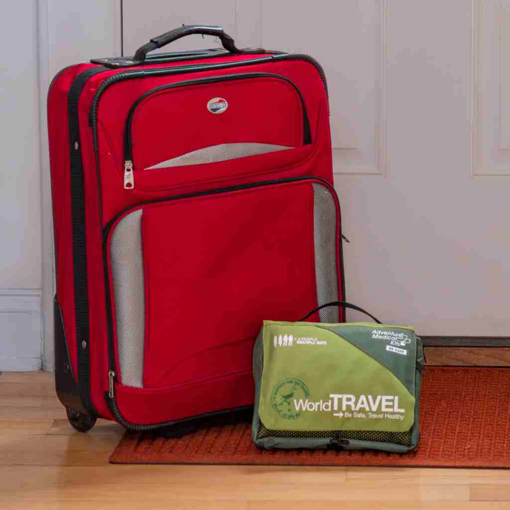Travel Series Medical Kit - World Travel in front of luggage and door