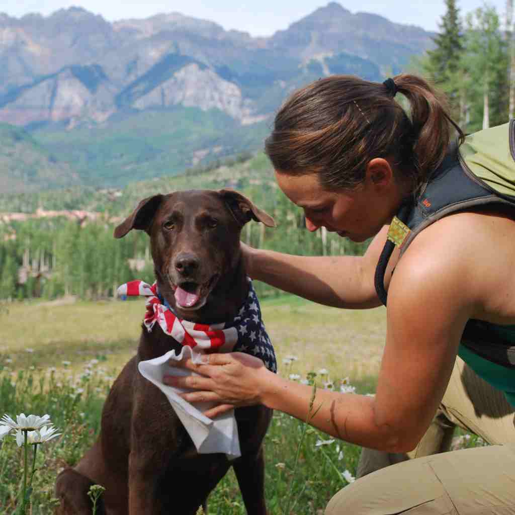Adventure Dog Wipes woman wiping dog's chest with mountains in the background