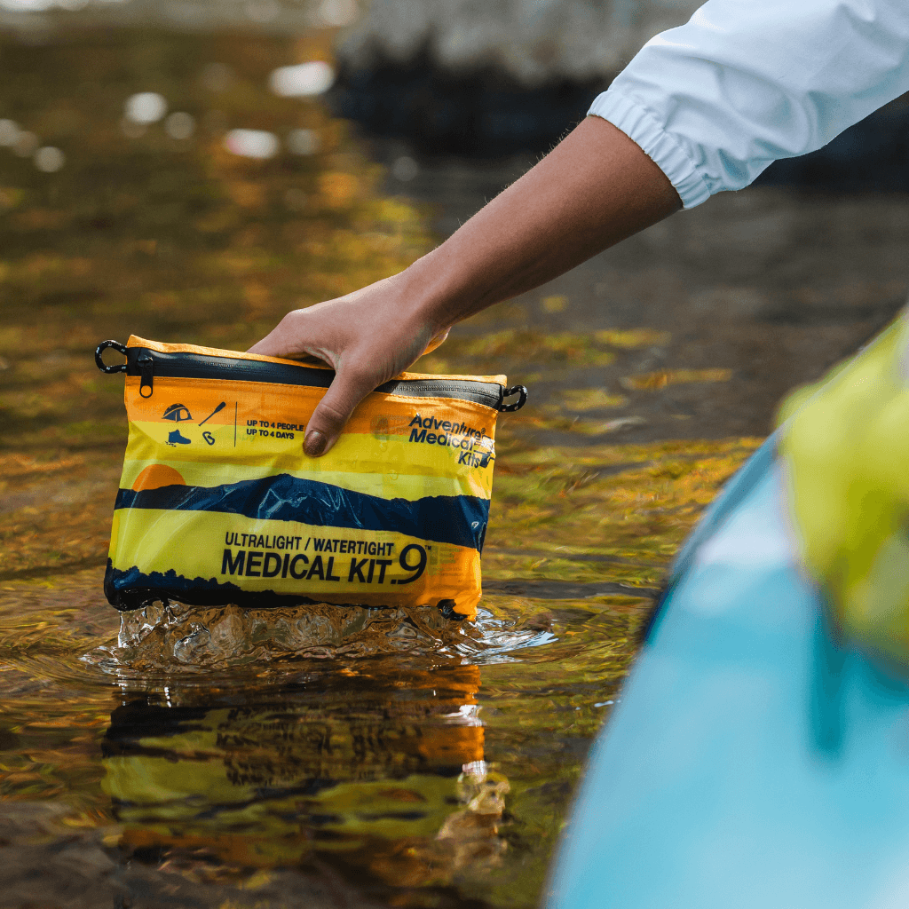 Ultralight / Watertight .9 Kit being dipped in water off the side of a kayak