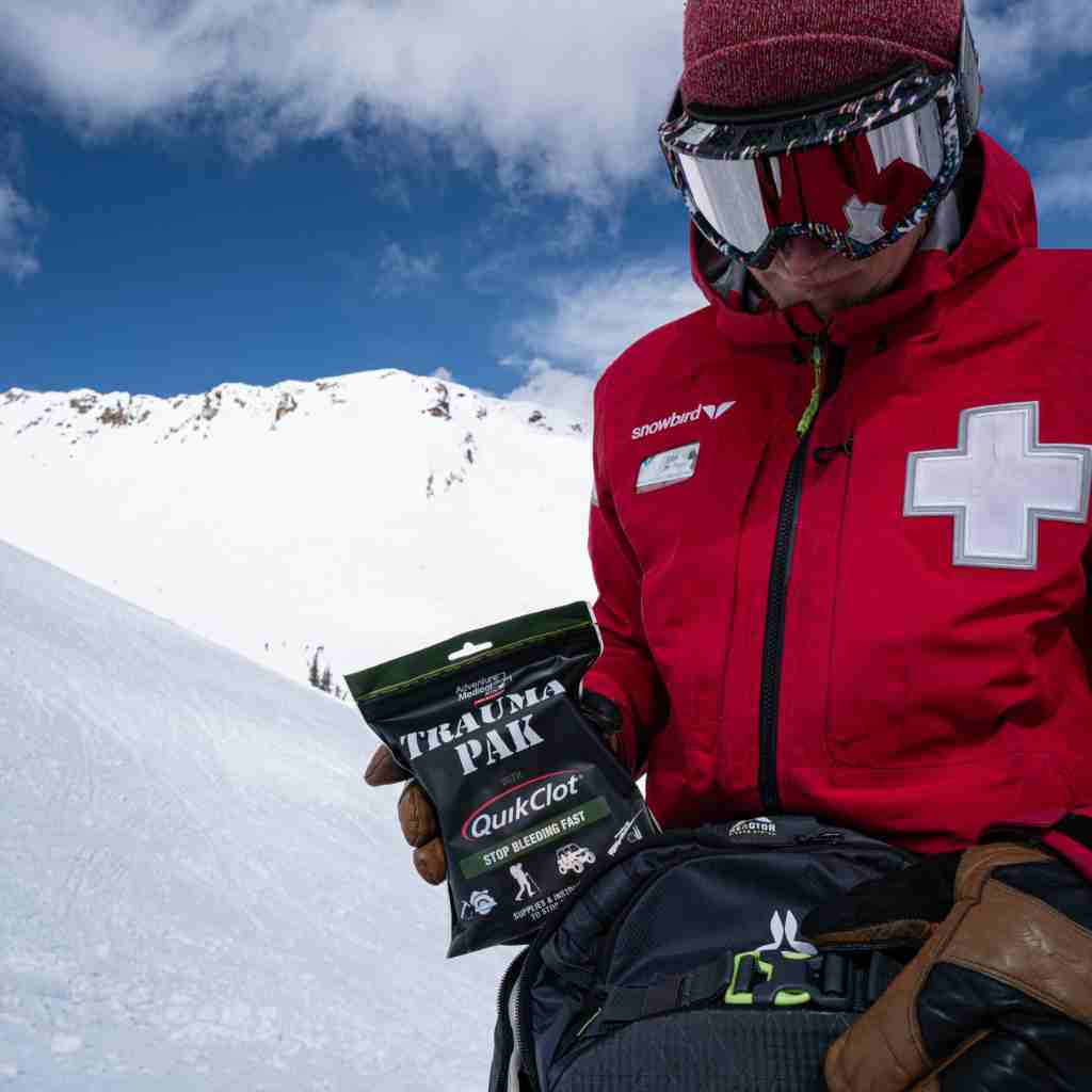 Trauma Pak First Aid Kit with QuikClot Ski Patrol removing kit from backpack with snow in background