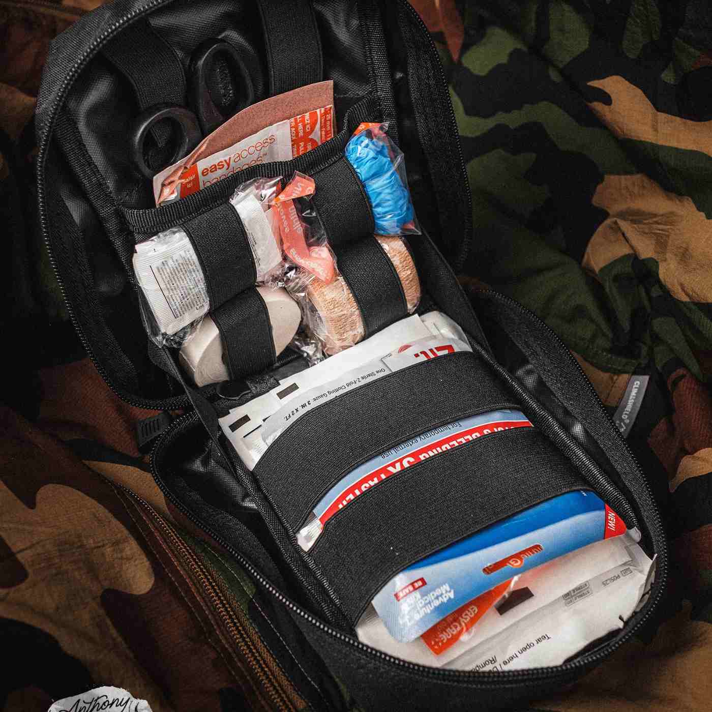 MOLLE Bag Trauma Kit 1.0 - Black kit opened laid on camo background
