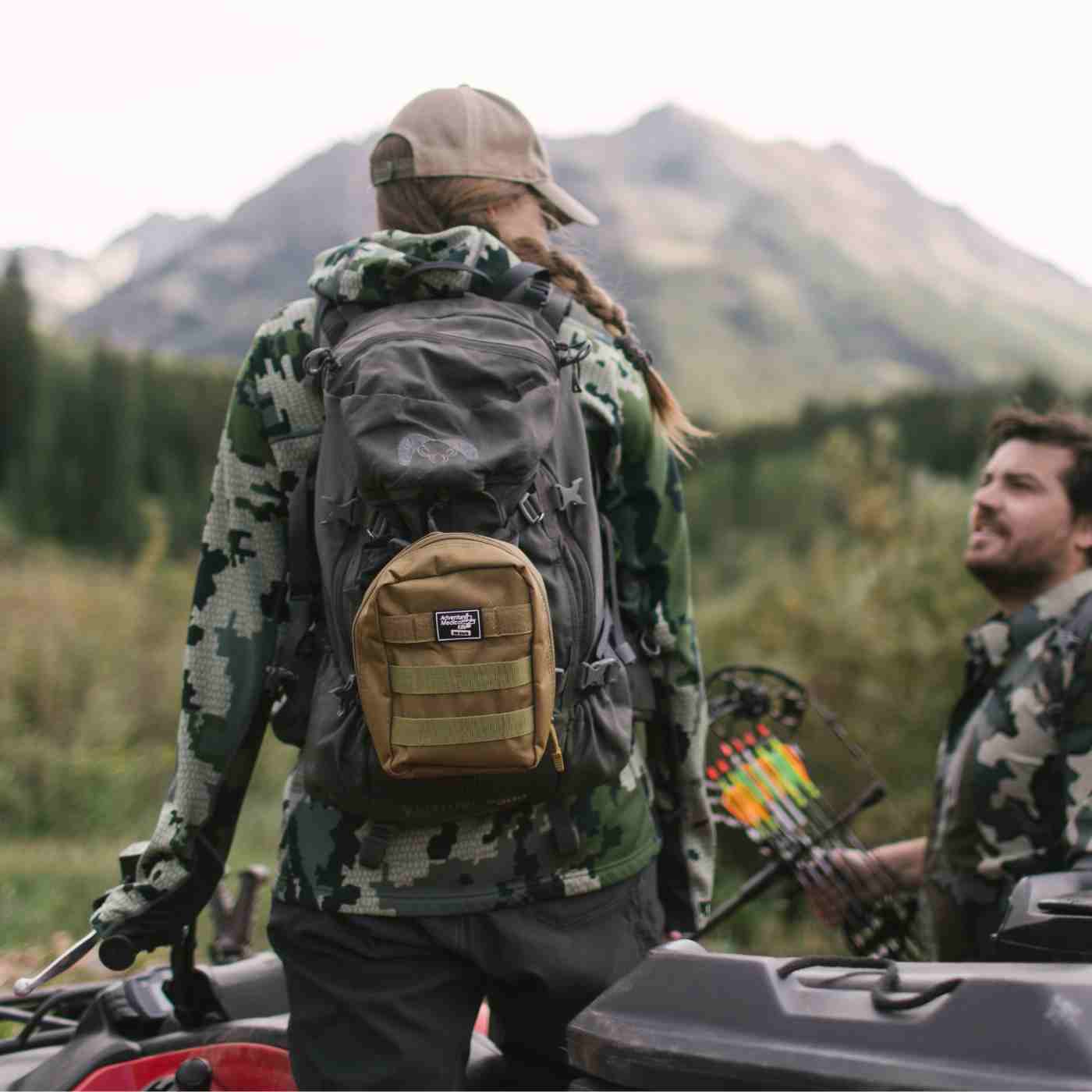 MOLLE Bag Trauma Kit 1.0 - Khaki woman with kit on backpack wearing camo standing on ATV next to man