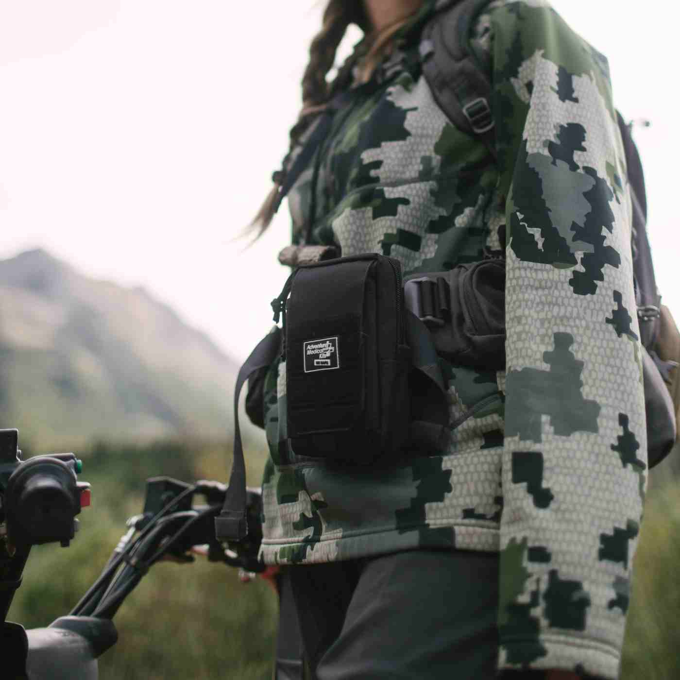 MOLLE Bag Trauma Kit 0.5 - Black on belt of woman in camo with mountains in background