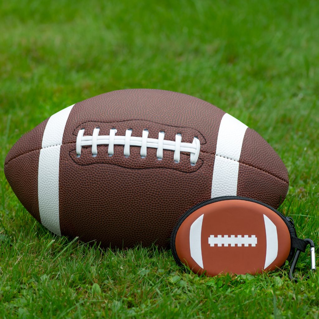 Football and small football-shaped first aid kit on grass