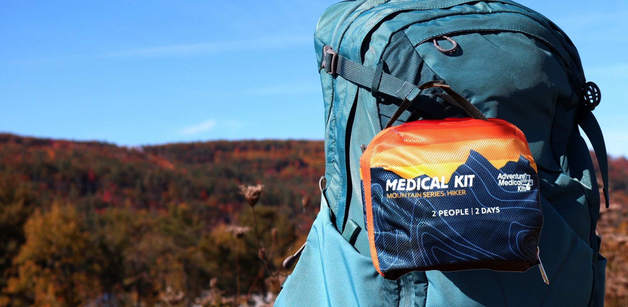 Sunset kit on blue backpack in front of fall background