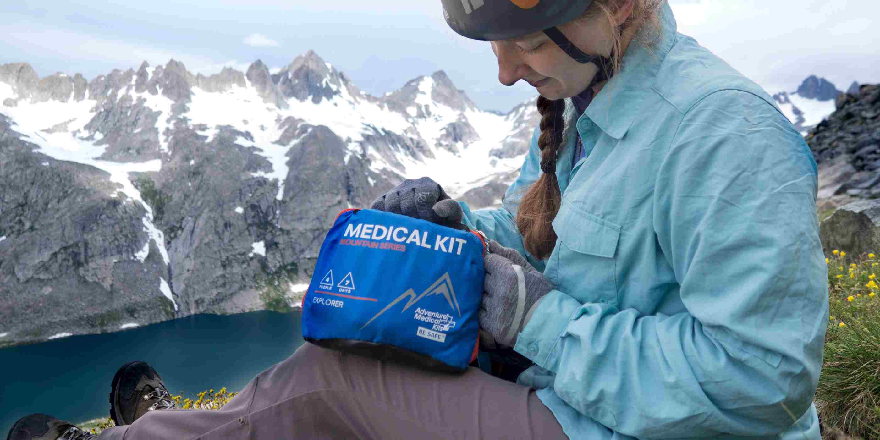 Mountain Series Medical Kit - Explorer woman in climbing gear opening kit in front of mountains