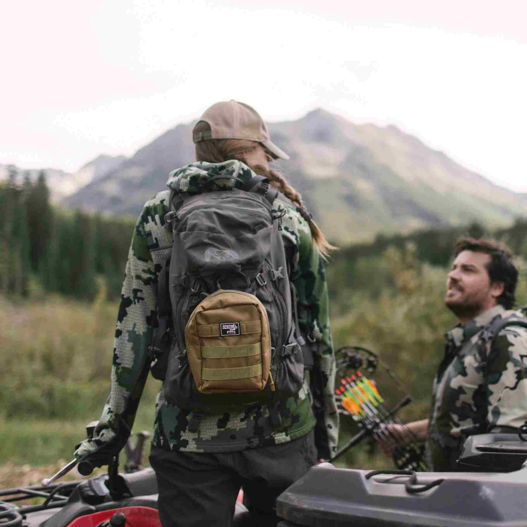 MOLLE Bag Trauma Kit 1.0 - Khaki woman with kit on backpack wearing camo standing on ATV next to man