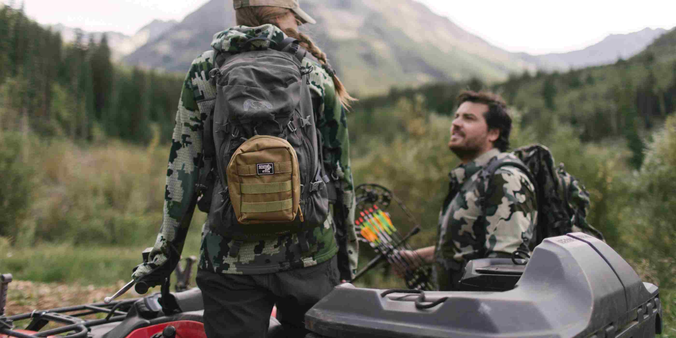 MOLLE Bag Trauma Kit 1.0 - Khaki woman with kit on backpack wearing camo standing on ATV next to man