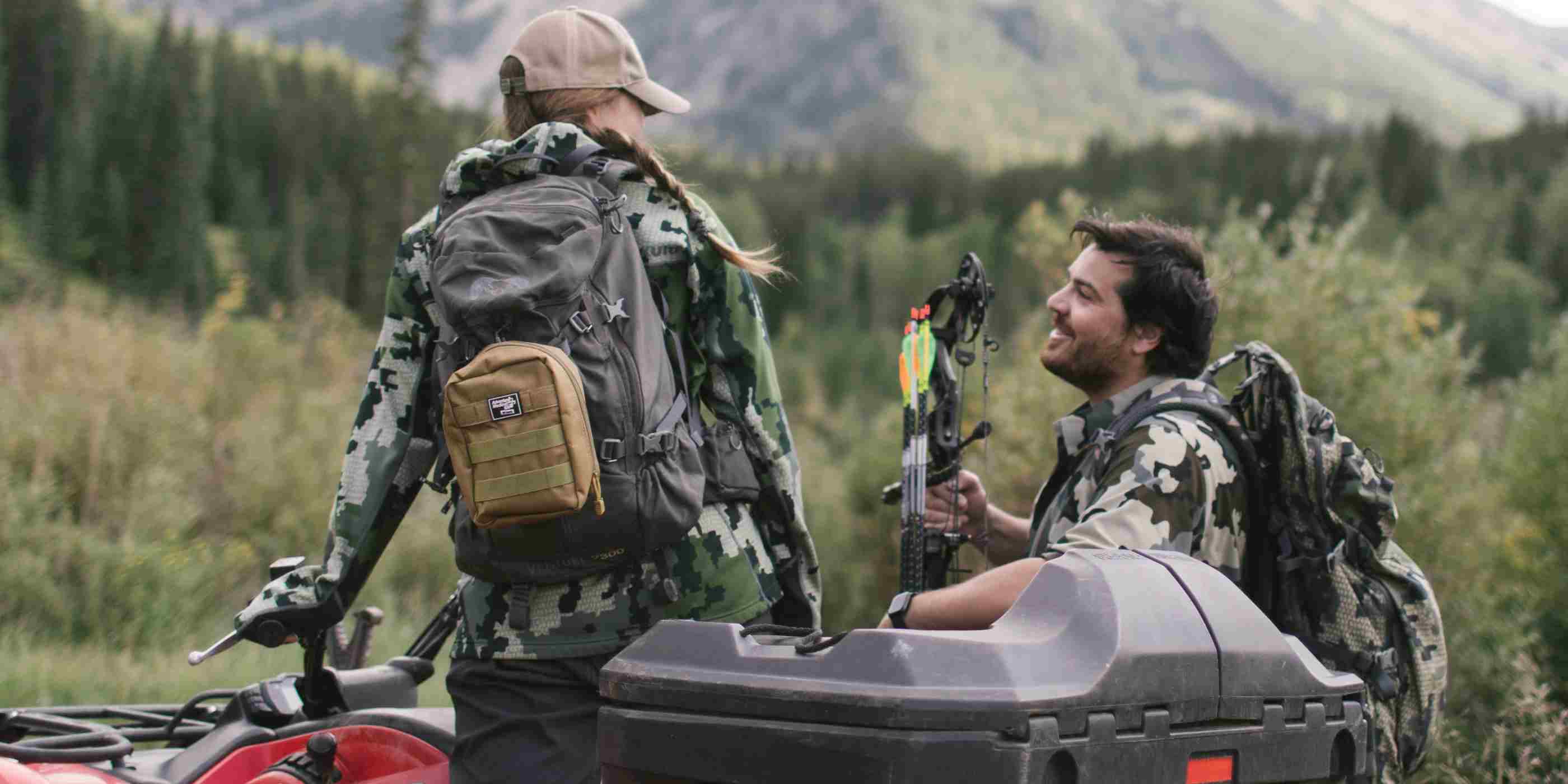 MOLLE Bag Trauma Kit 2.0 - Khaki kit attached to backpack of woman in camo on ATV next to man with bow and arrow