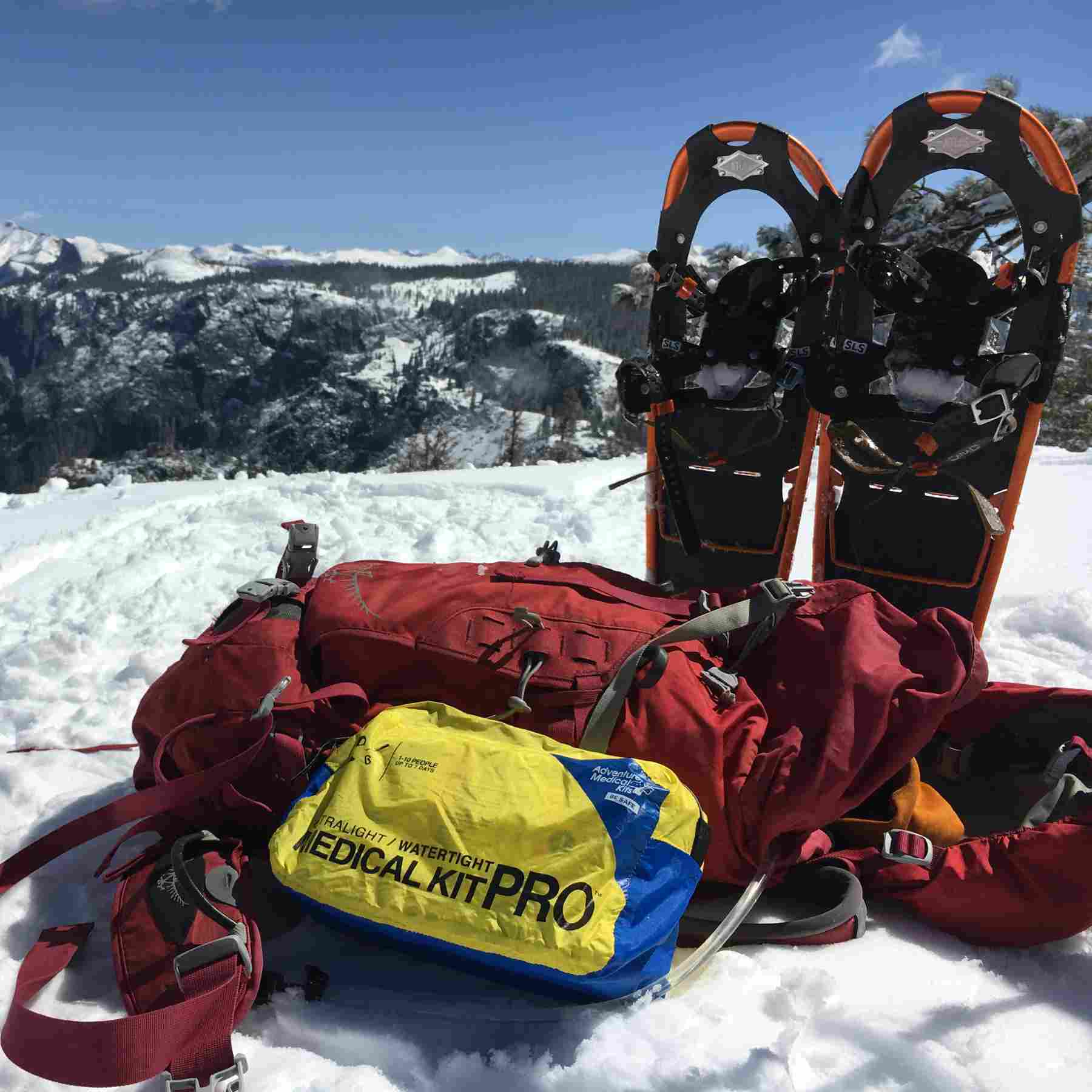 Ultralight/Watertight Medical Kit - Pro next to backpack and snowshoes in the snow