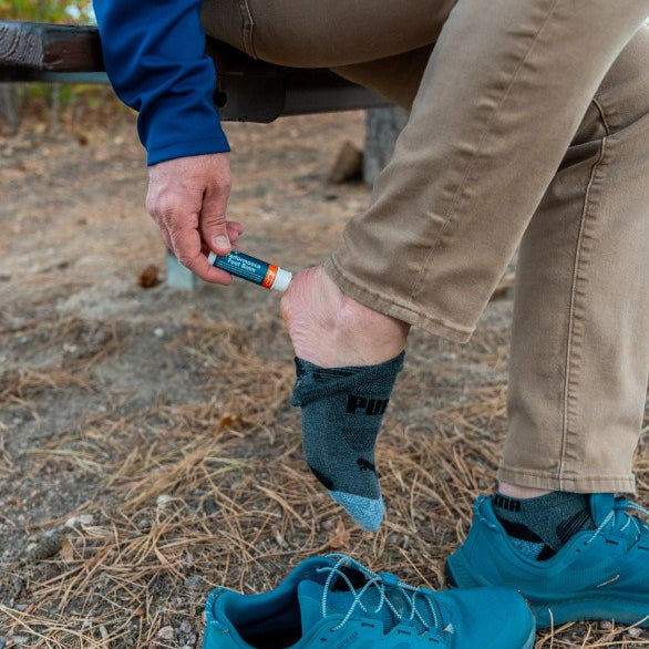 adult applying foot balm to foot outdoors