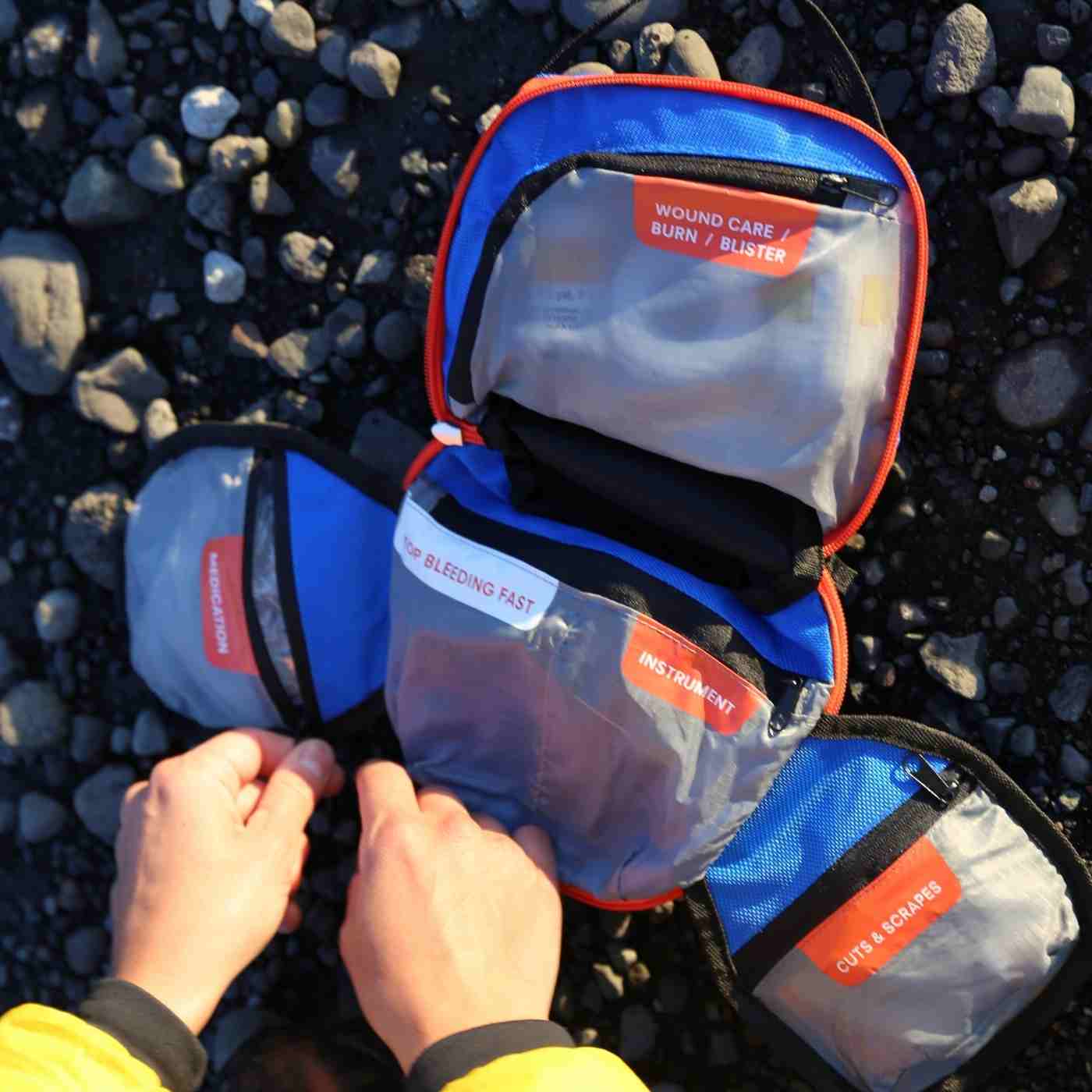 Mountain Series Medical Kit - Backpacker person opening kit on rocky ground