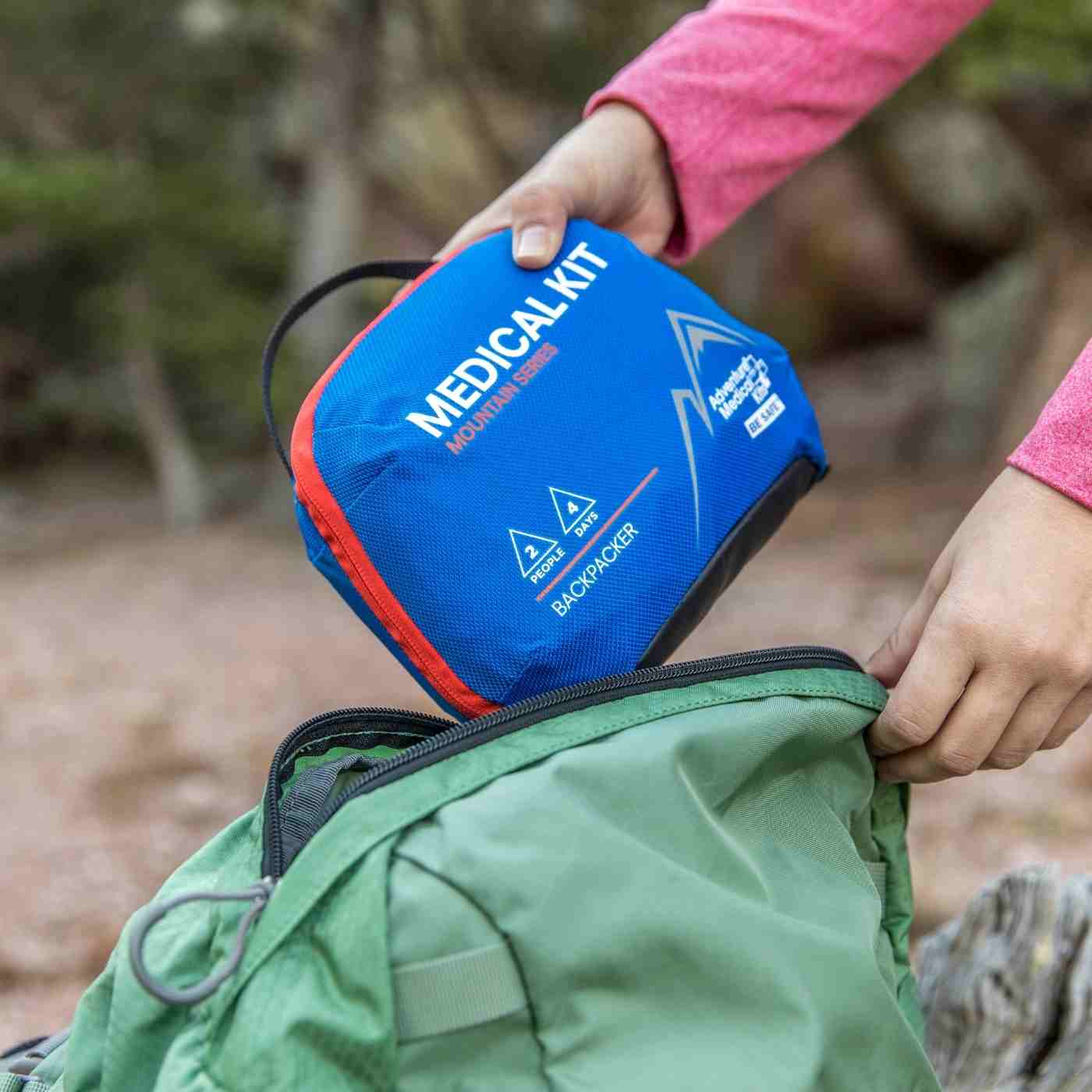 Mountain Series Medical Kit - Backpacker woman pulling out of green backpack