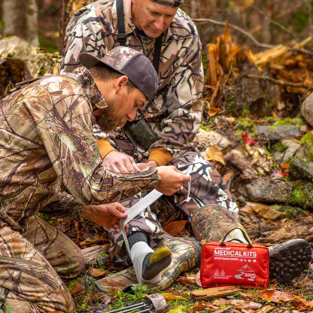 Sportsman Series Medical Kit - 200 hunter wrapping friend's leg with kit next to them