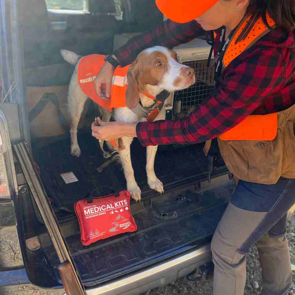 Sportsman Series Medical Kit - 300 woman putting vest on hunting dog with kit next to them