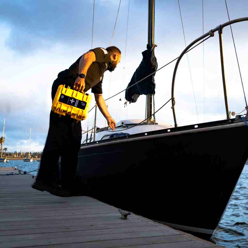 Marine Series Medical Kit - 600 man holding while reaching on boat