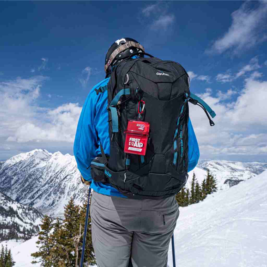 Adventure First Aid, Water-Resistant Kit kit on backpack of person skiing on snowy mountain