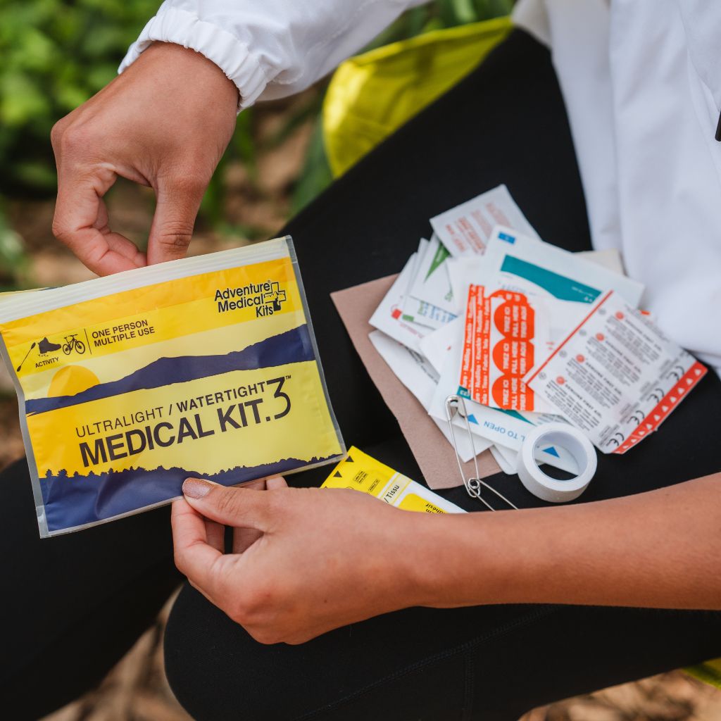 Person holding an ultralight/watertight medical kit with additional supplies on a natural background