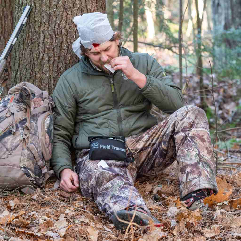 Tactical Medical Kit - Field Trauma with QuikClot hunter man using kit while seated with head injury