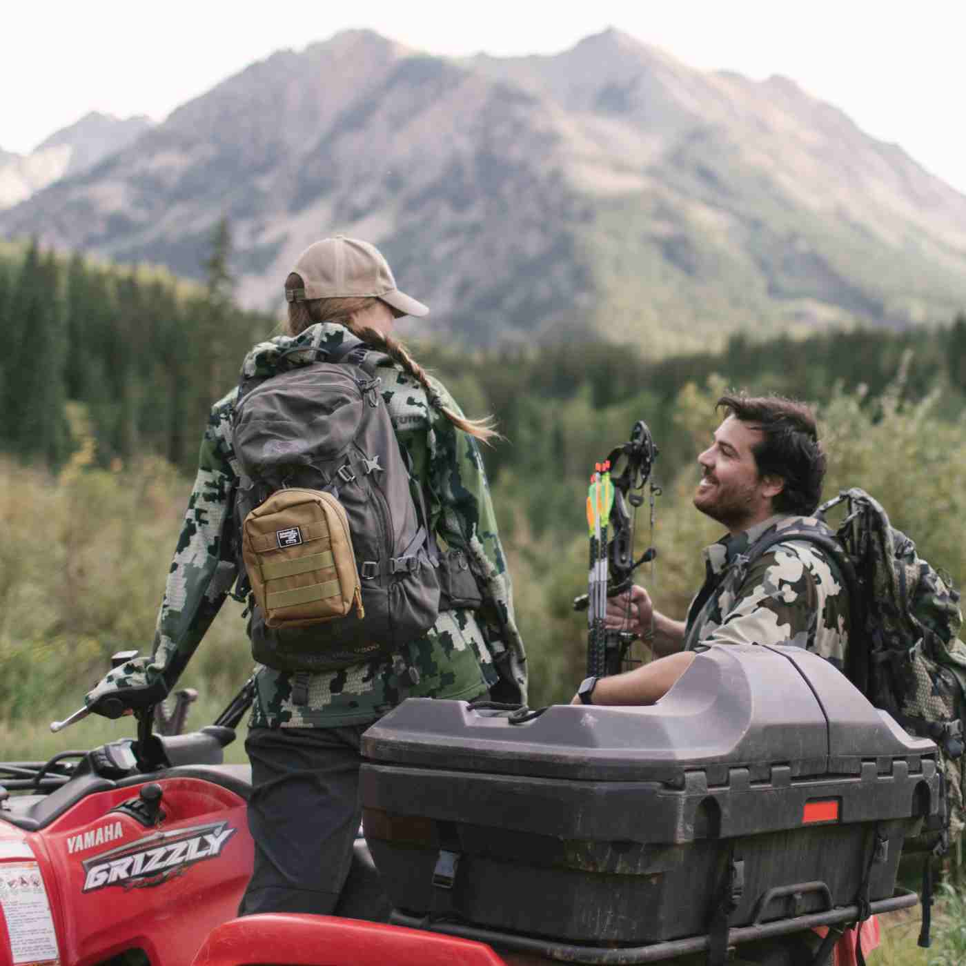 MOLLE Bag Trauma Kit 2.0 - Khaki kit attached to backpack of woman in camo on ATV next to man with bow and arrow