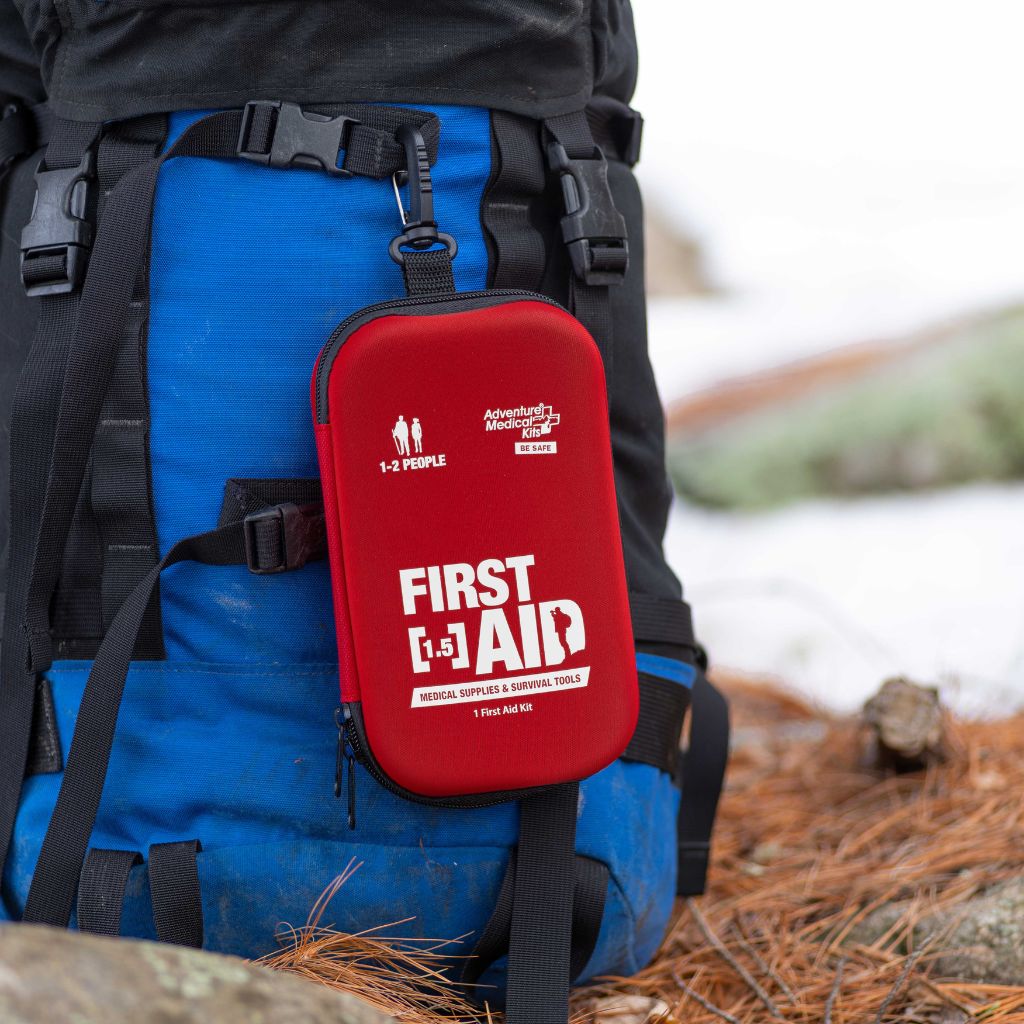 Adventure Frst Aid 1.5 kit attached to a blue backpack with a natural background