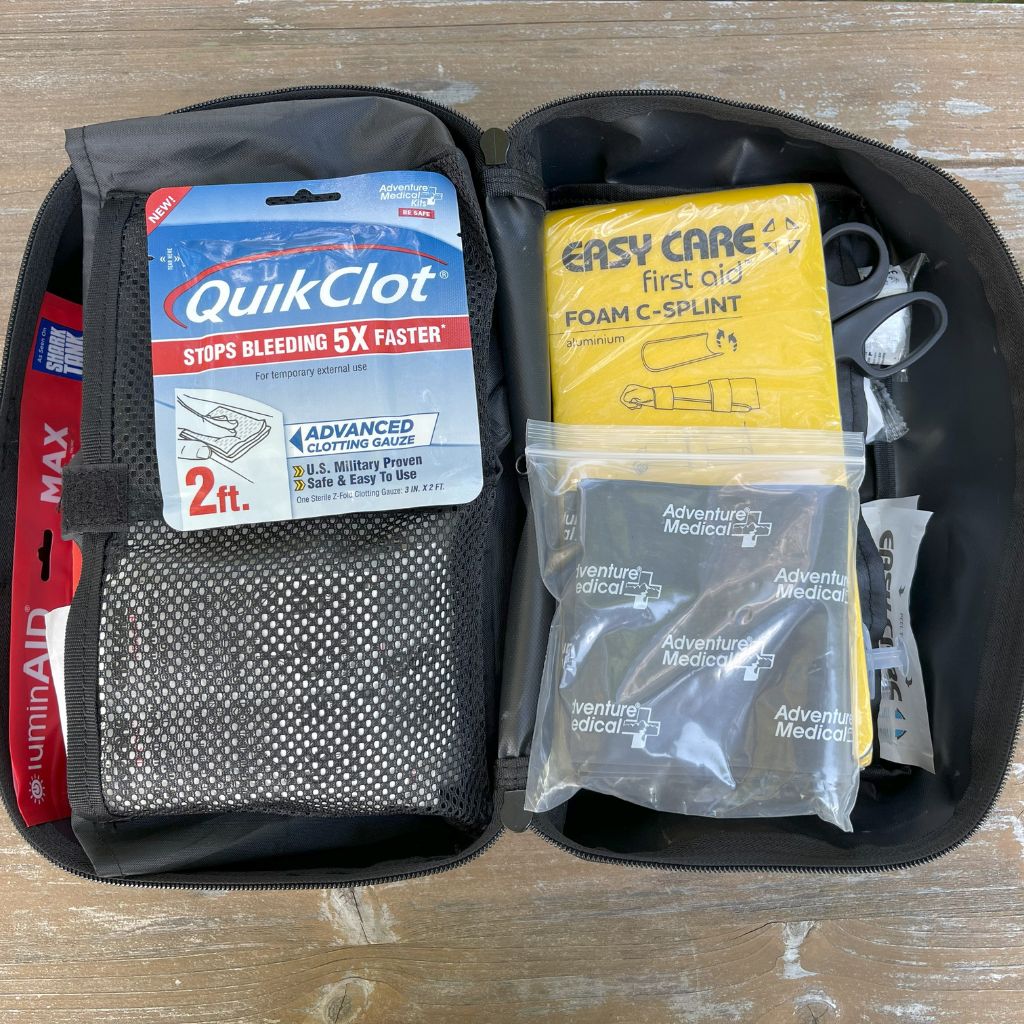 MOLLE Pro first aid kit with QuikClot and Easy Care foam C-splint on a wooden surface