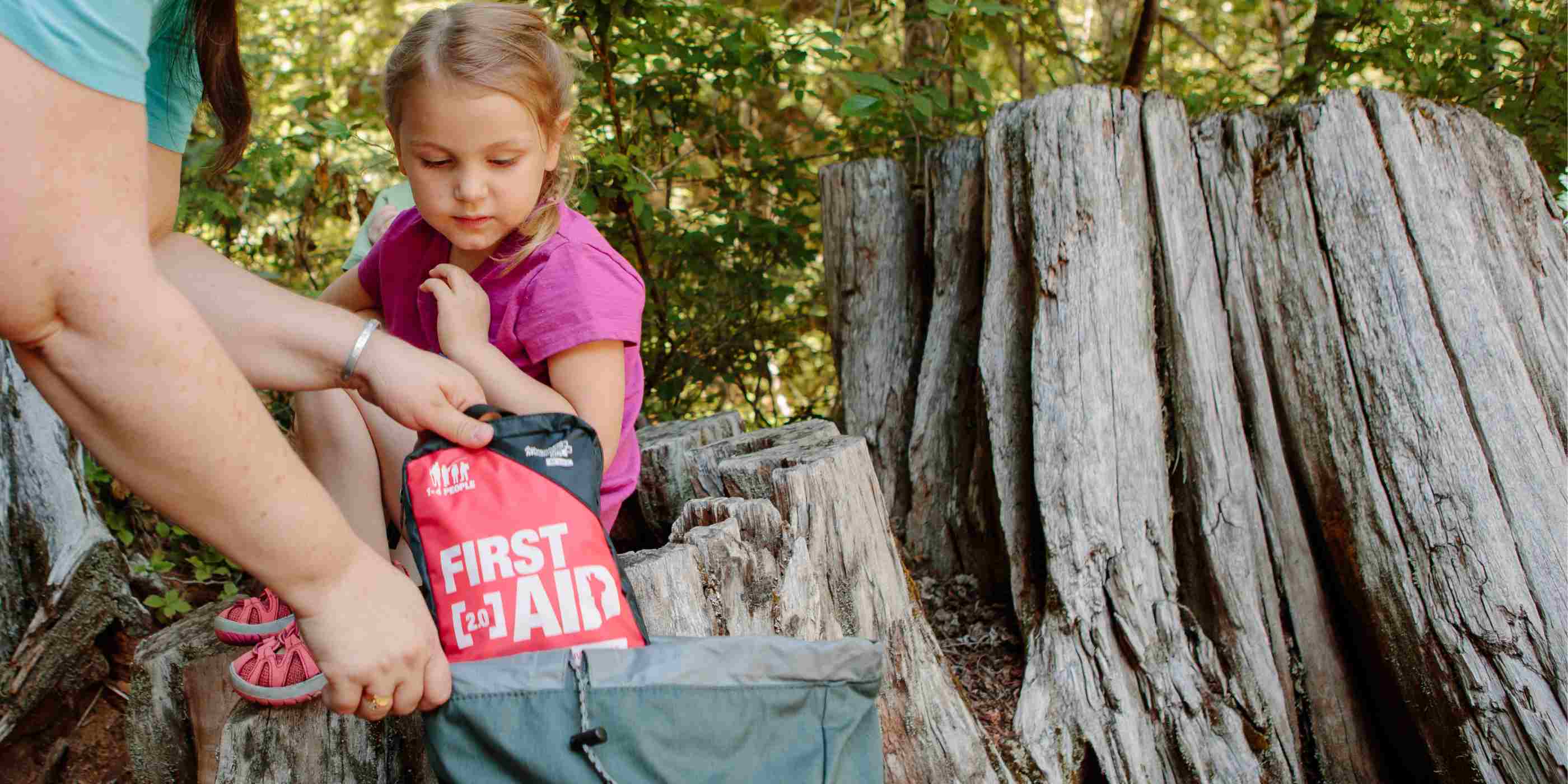 Adventure First Aid, 2.0 woman pulling kit from backpack next to child