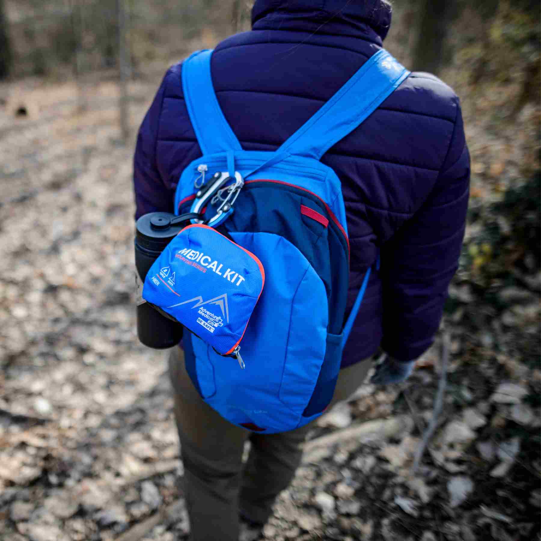 Mountain Series Medical Kit - Hiker kit hanging from blue backpack of person walking