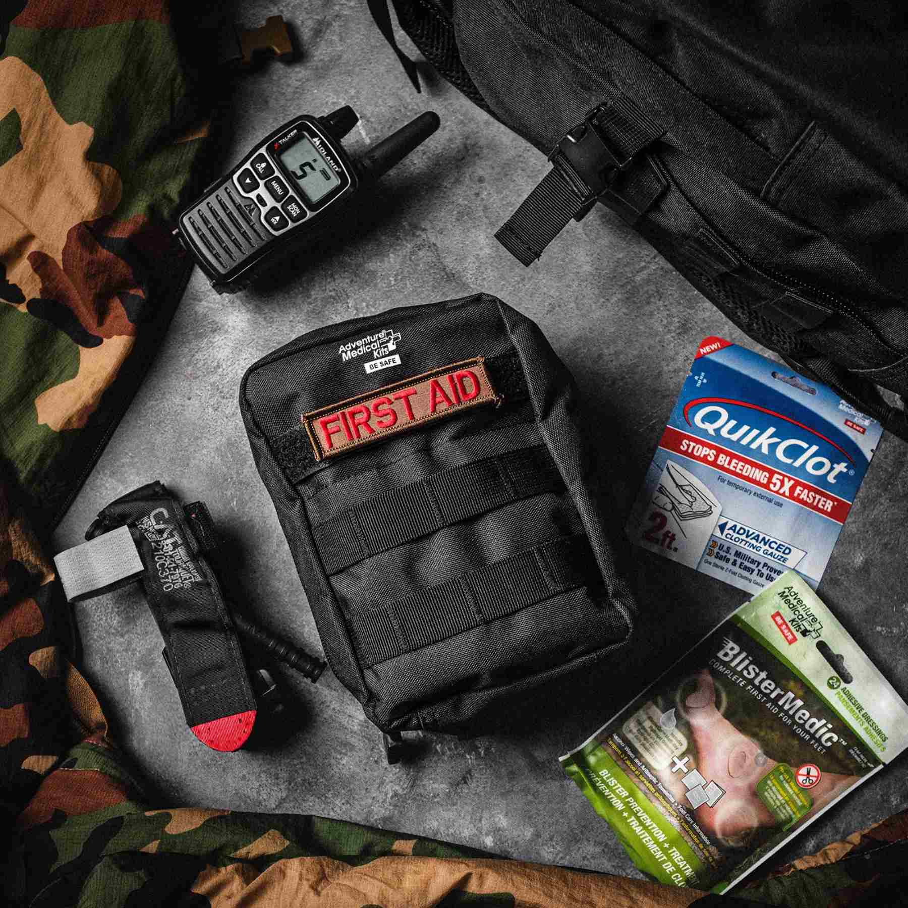 MOLLE Bag Trauma Kit 1.0 - Black with First Aid patch next to QuikClot, radio, and Blister Medic