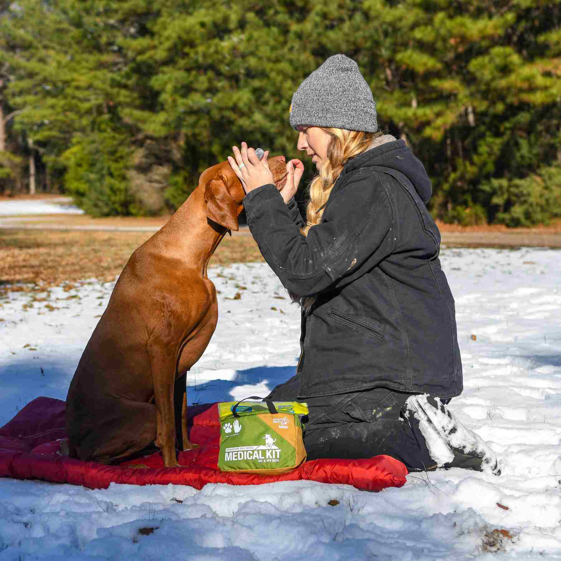 Adventure Dog Medical Kit - Me & My Dog placed on blanket in snow in front of woman and brown dog