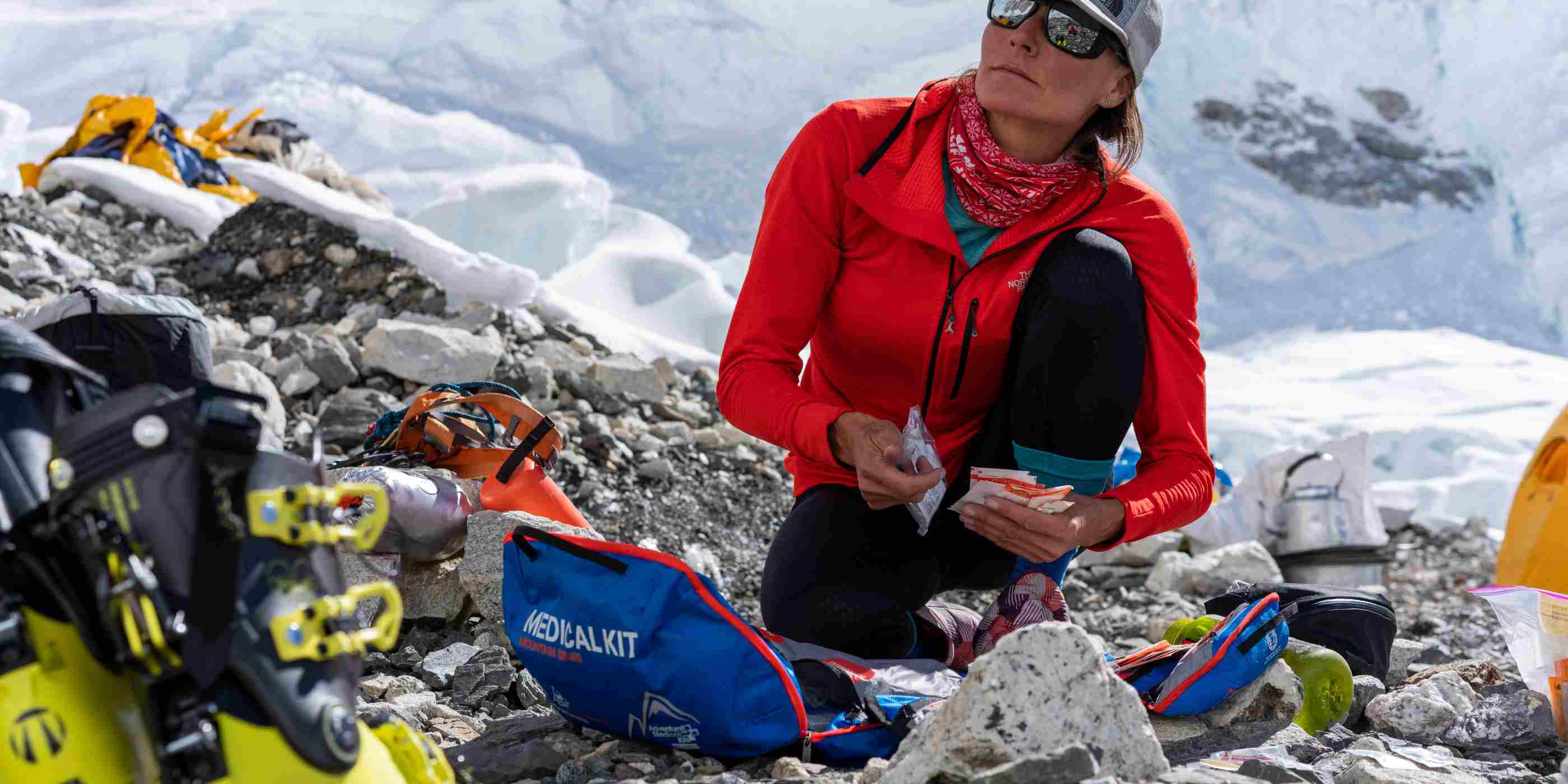 Mountain Series Medical Kit - Mountaineer woman removing kit contents on rocky ground and snow