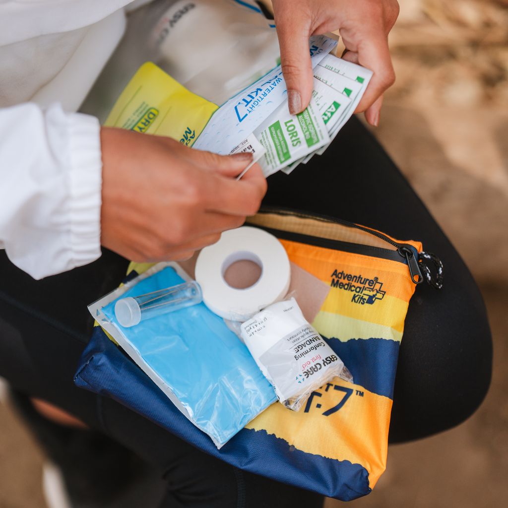 Person organizing items from an Adventure Medical Kits first aid kit.