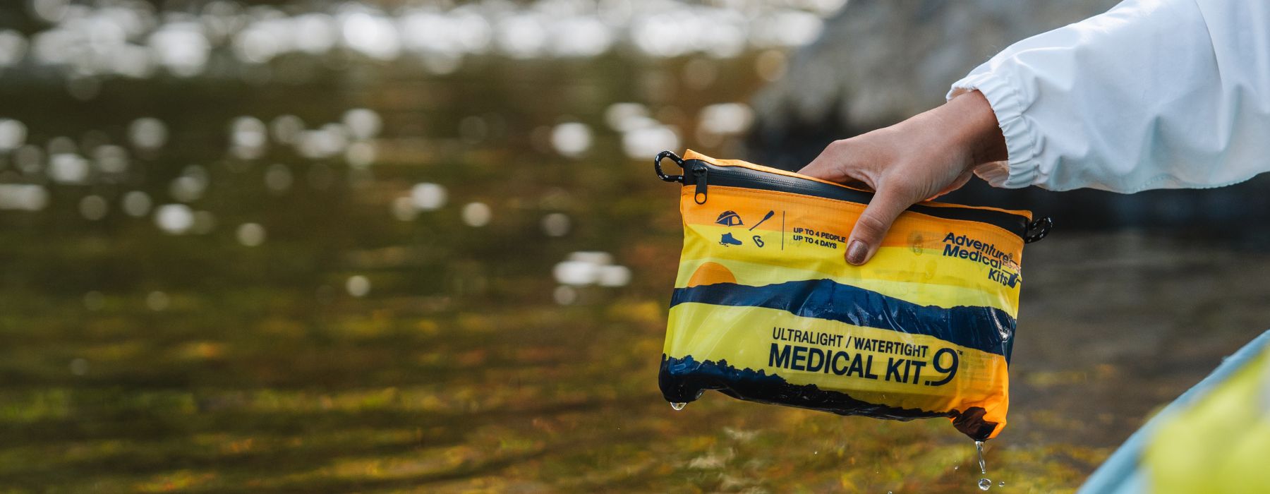 Close-up of a hand pulling the Ultralight / Watertight Medical Kit .9 out of the water